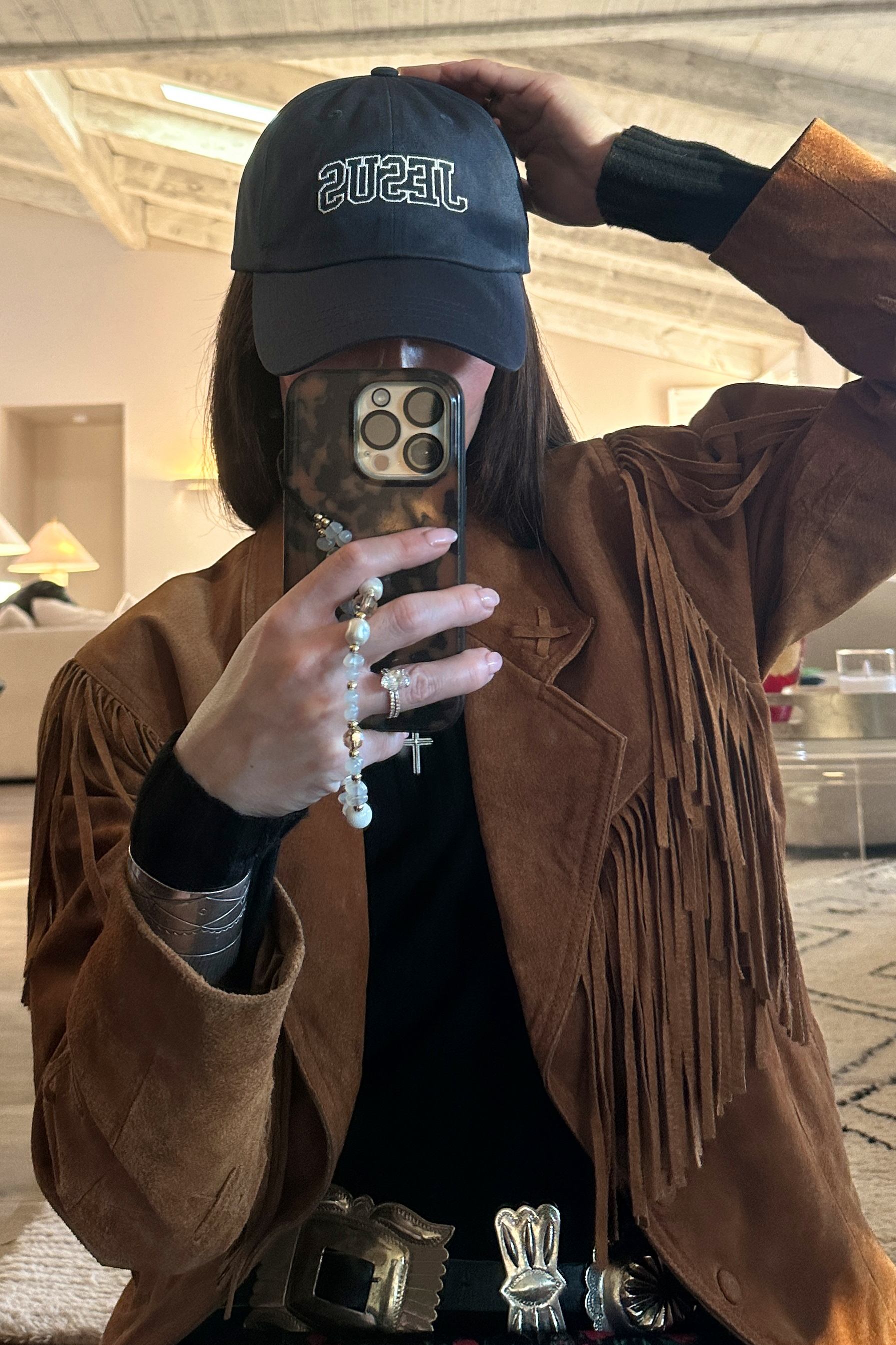 Person wearing a blue cap and brown jacket taking a mirror selfie.